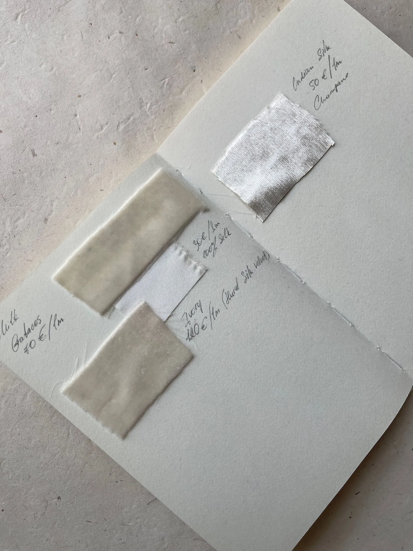 Tygprover i naturtoner fästa i en anteckningsbok